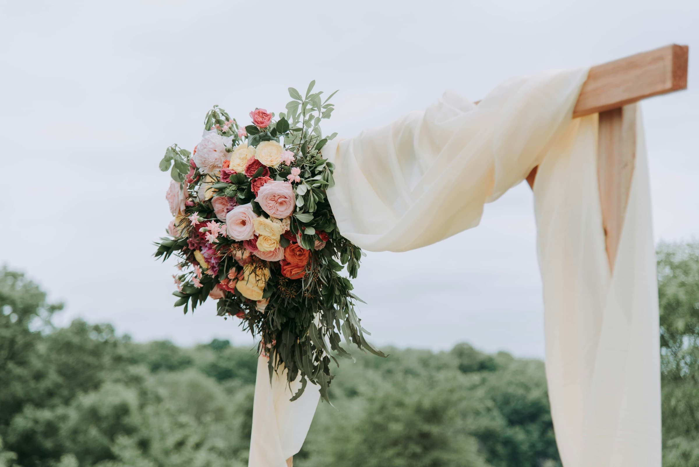 Floral arrangement on a wooden wedding arch outdoors