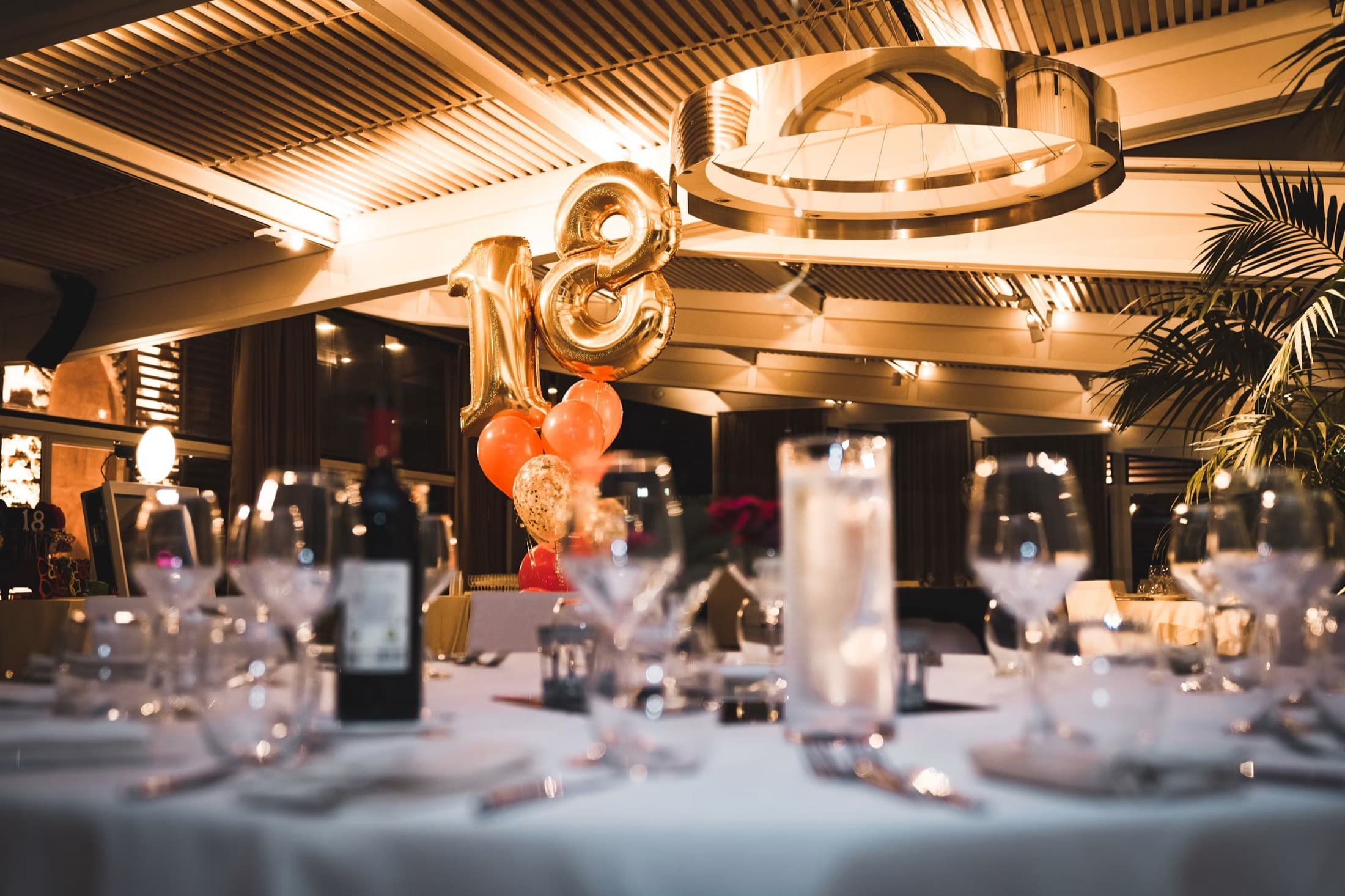 Candlelit tables set for a milestone birthday celebration with balloons